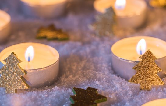 Advent and christmas candlelights with golden shiny christmas trees on white snow