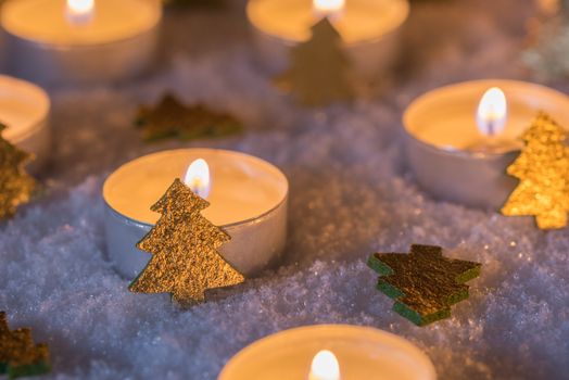 Advent and Christmas mood with candles and golden christmas trees on cold snow