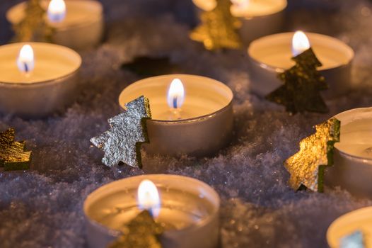 Christmas winter candle flames on snow, festive mood at winter night 