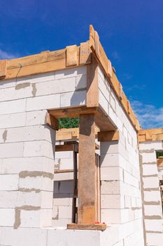 Building site of a house under construction: walls of gas concrete blocks, wooden reinforcement of windows and concrete foundation.