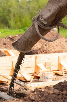 Lay of the cement or concrete into the foundation formwork with automatic pump. Building house foundation