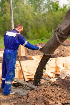 Construction worker laying cement or concrete into the foundation formwork. Building house foundation