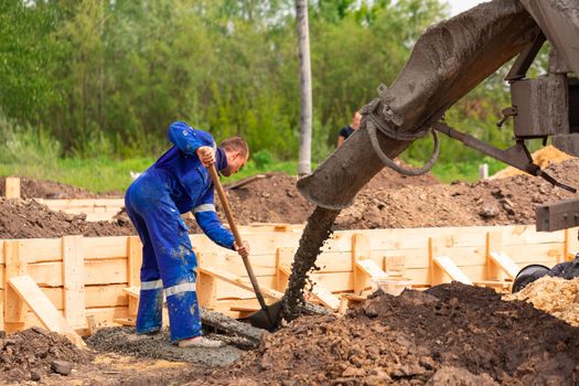 Construction worker laying cement or concrete into the foundation formwork. Building house foundation