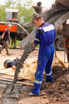 Construction worker laying cement or concrete into the foundation formwork. Building house foundation