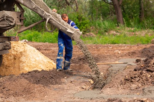 Construction worker laying cement or concrete into the foundation formwork. Building house foundation