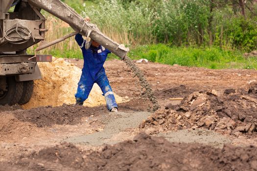 Construction worker laying cement or concrete into the foundation formwork. Building house foundation