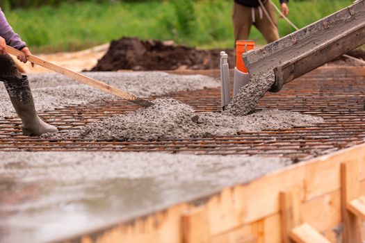 Lay of the cement or concrete into the foundation formwork from concrete mixer. Building house foundation