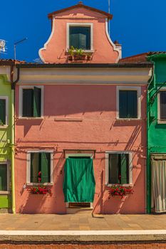 Rusty Red house with green curtain in Burano