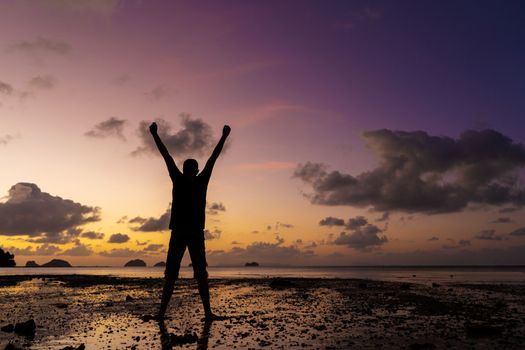 Silhouette of a man on the beach at sunset. Man rejoices meets the sunset.