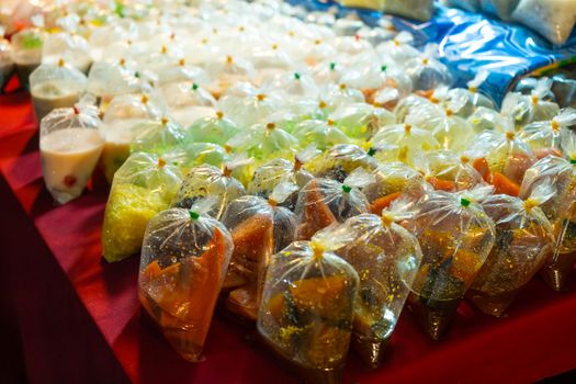 Colored desserts in plastic bags at a street food market in Asia. Unusual Asian food