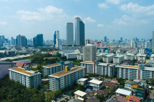 View from the high floor of the streets of Bangkok. Tall buildings and roofs of small houses. City landscape.