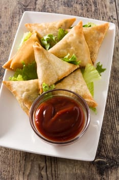 Samsa or samosas with meat and vegetables on wooden table. Traditional Indian food.