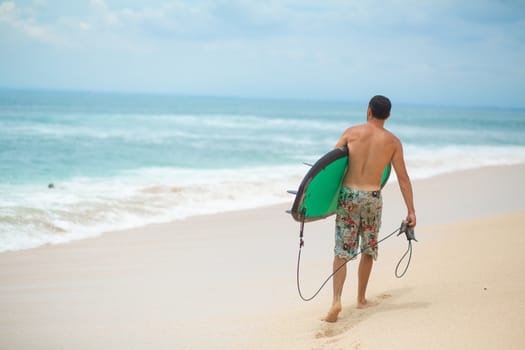 Surfer. Surfing Man With Surfboard Walking On Sandy tropical Beach. Healthy Lifestyle, water activities, Water Sport. Beautiful Ocean