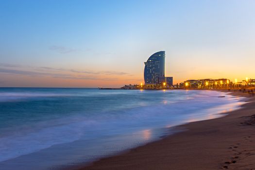 The beach of Barcelona with a modern skyscraper at sunset