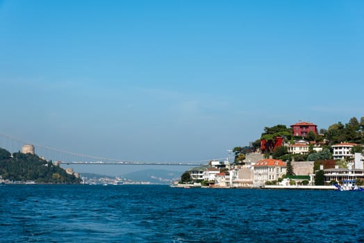 The Bosphorus in Istanbul with a houses at the shore and the second Bosphorus Bridge in the distance