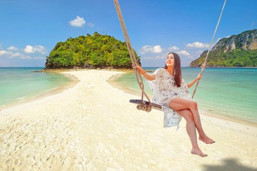 Beautiful woman sitting on a swing on the beach  in Krabi, Thailand