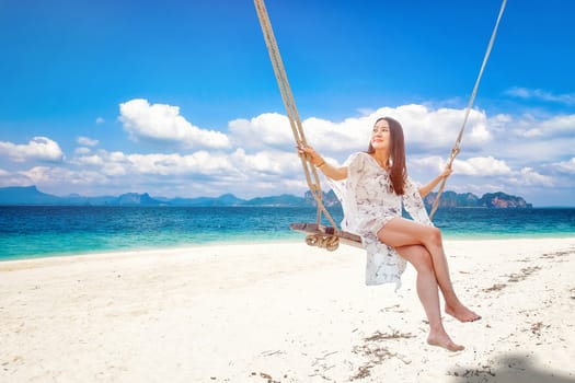 Beautiful woman sitting on a swing on the beach  in Krabi, Thailand