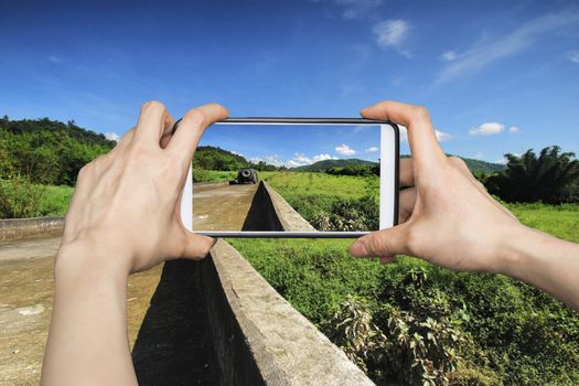 Girl taking pictures on mobile smart phone in Way to Off-road adventures into the mountains and blue sky, in the forests.