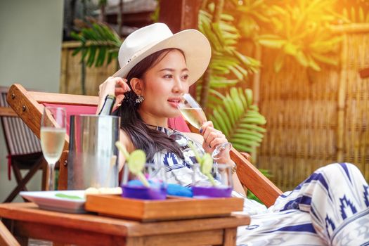 Beautiful young woman lying on a deckchair with a champagne in her hands