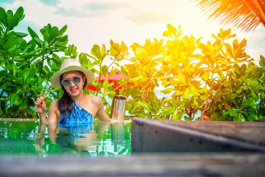 Beautiful young woman in swimming pool with a champagne in her hands

