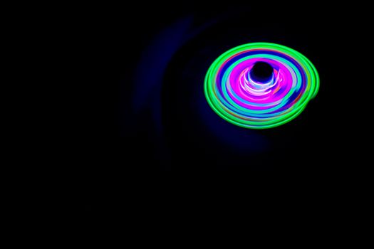 Long exposure photograph of a light spinning top with black background.