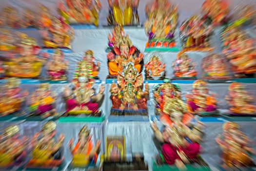 Zoom burst photograph of Lord Ganesh idol in the center of idols in a shop. Can be used as background.
