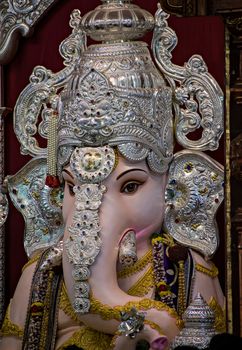As per ritual during Ganeshotsav festival -Close up portrait view of decorated and garlanded  idol of Hindu God Ganesha in Pune ,Maharashtra, India.