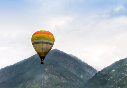 Isolated image of hot air balloon high in the air on a clear background of blue sky  in Manali, Himachal Pradesh, India.