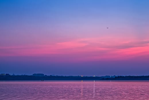 An aircraft approaching airport glides over Ambazari lake, Nagpur, india  with a backdrop of Sunset on a beautiful evening.     Can be used as wallpaper.