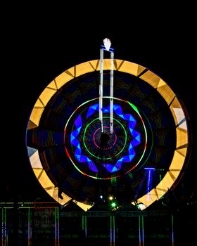 Fun fair Giant Ferris wheel spinning at night. Slow shutter photograph of a rotating giant wheel at night.