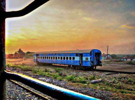 View from a train widow of an abandoned  railway coach spotted with nice Sunrise near Hubbali, India.