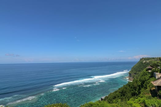 Beautiful blue sunset on the ocean with big waves and cliffs and cliffs. Bali island with its tropical and exotic nature. Sunrise over the sea and ocean. Phantom blue in sunset.