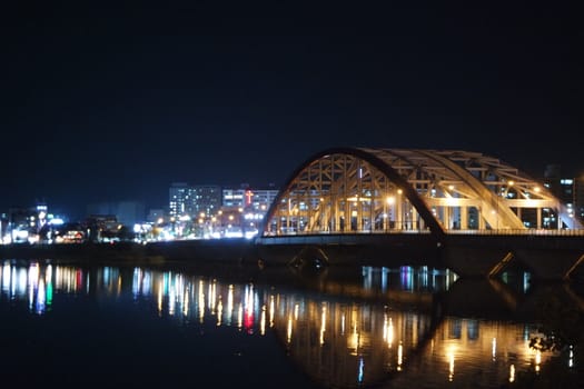 Night view of a beautiful scene of bridge over sea water in the evening time with colorful lights.