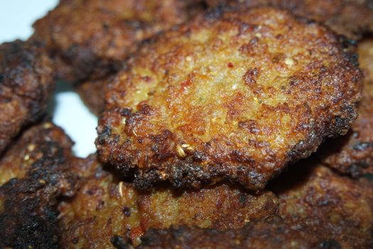 Delicious spicy fried round kebab served in a white ceramic plate on wooden floor