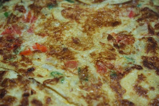 Close-up view with selective focus of egg omelet with peppers and spices sprinkled