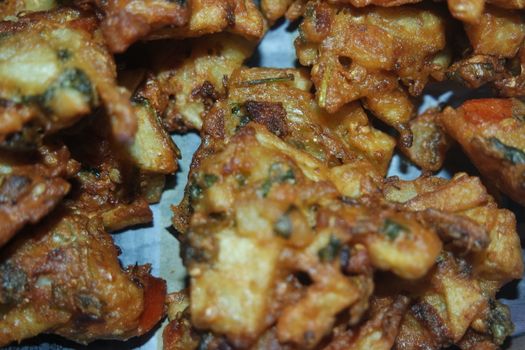 close-up view with selective focus of crispy basin pakora/pakoda or patties are popular indian or pakistani street food snack, served with green salad and sauce. Selective focus of