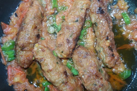 Closeup view of delicious spicy home made fried kebab with green mint leaves and green pepper sprinkled on it