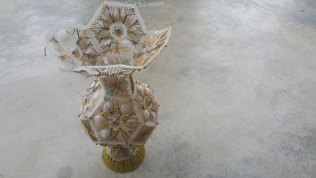 A beautiful ceramic vase placed on a grey floor. The ceramic vase has lovely designs and is used for flowers or bouquet