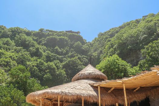 Wooden bungalow on white sand beach in tropical paradise. Wooden cottage with a reed roof on the island of Gili Meno in Indonesia. Simple bamboo fence and tropical vegetation around the cottage.