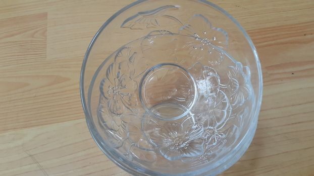 Top view of empty white glass bowls on a wooden floor. Glass bowl with flowers made on its wall