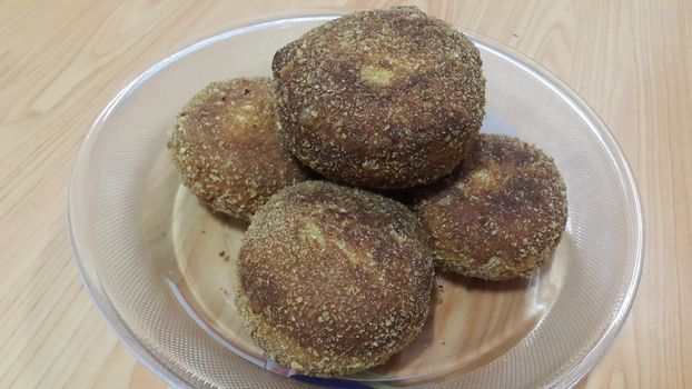 Closeup perspective view of fried pizza bomb or pizza balls served in a glass plate over wooden floor. Pizza bombs are delicious and tasty altered form of pizza.