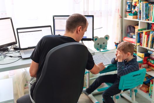 Father with kid trying to work from home during quarantine. Stay at home, work from home concept during coronavirus pandemic