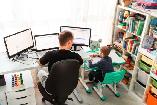 Father with kid trying to work from home during quarantine. Stay at home, work from home concept during coronavirus pandemic