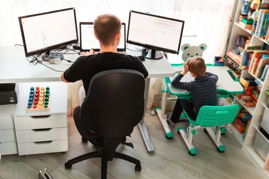 Father with kid trying to work from home during quarantine. Stay at home, work from home concept during coronavirus pandemic