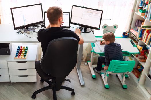 Father with kid trying to work from home during quarantine. Stay at home, work from home concept during coronavirus pandemic