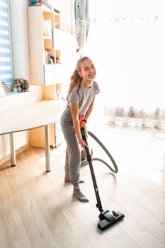 Teenage girl cleaning her room with vacuum cleaner. Children's tidiness and housekeeping help concept