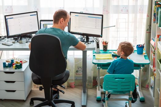 Father with kid trying to work from home during quarantine. Stay at home, work from home concept during coronavirus pandemic