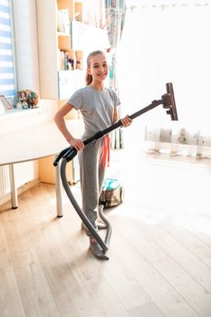 Teenage girl cleaning her room with vacuum cleaner. Children's tidiness and housekeeping help concept