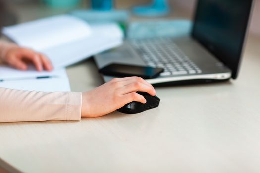 Close up of young school girl working at home in her room with a laptop and class notes studying in a virtual class. Distance education and e-learning, online learning concept during quarantine