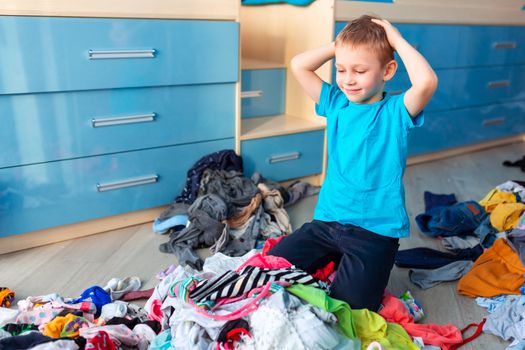 Small boy desperate with the mess in his clothes in his bedroom.